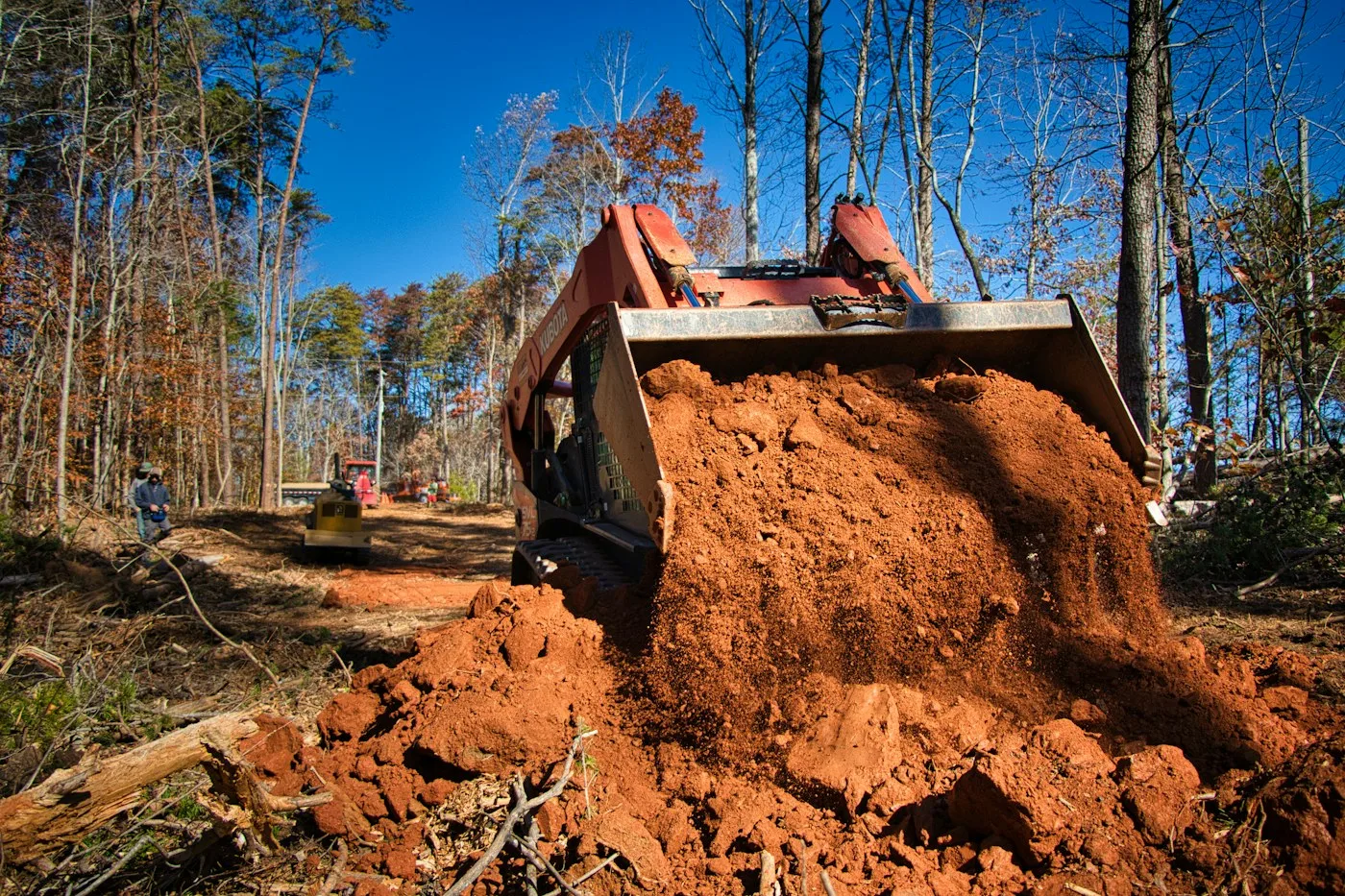 Loader moving soil in a wooded area